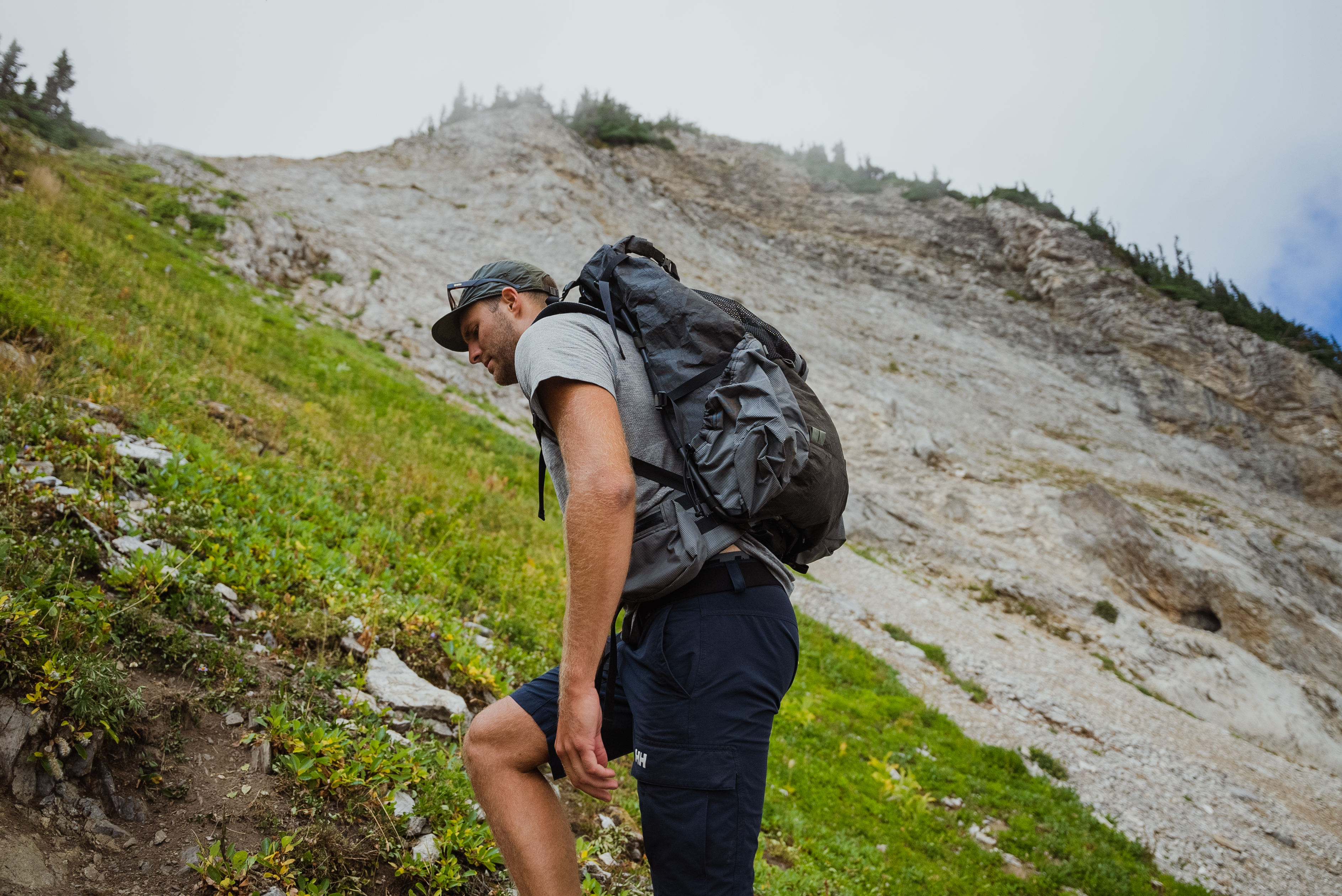 backpacker scrambles up a rocky mountainside