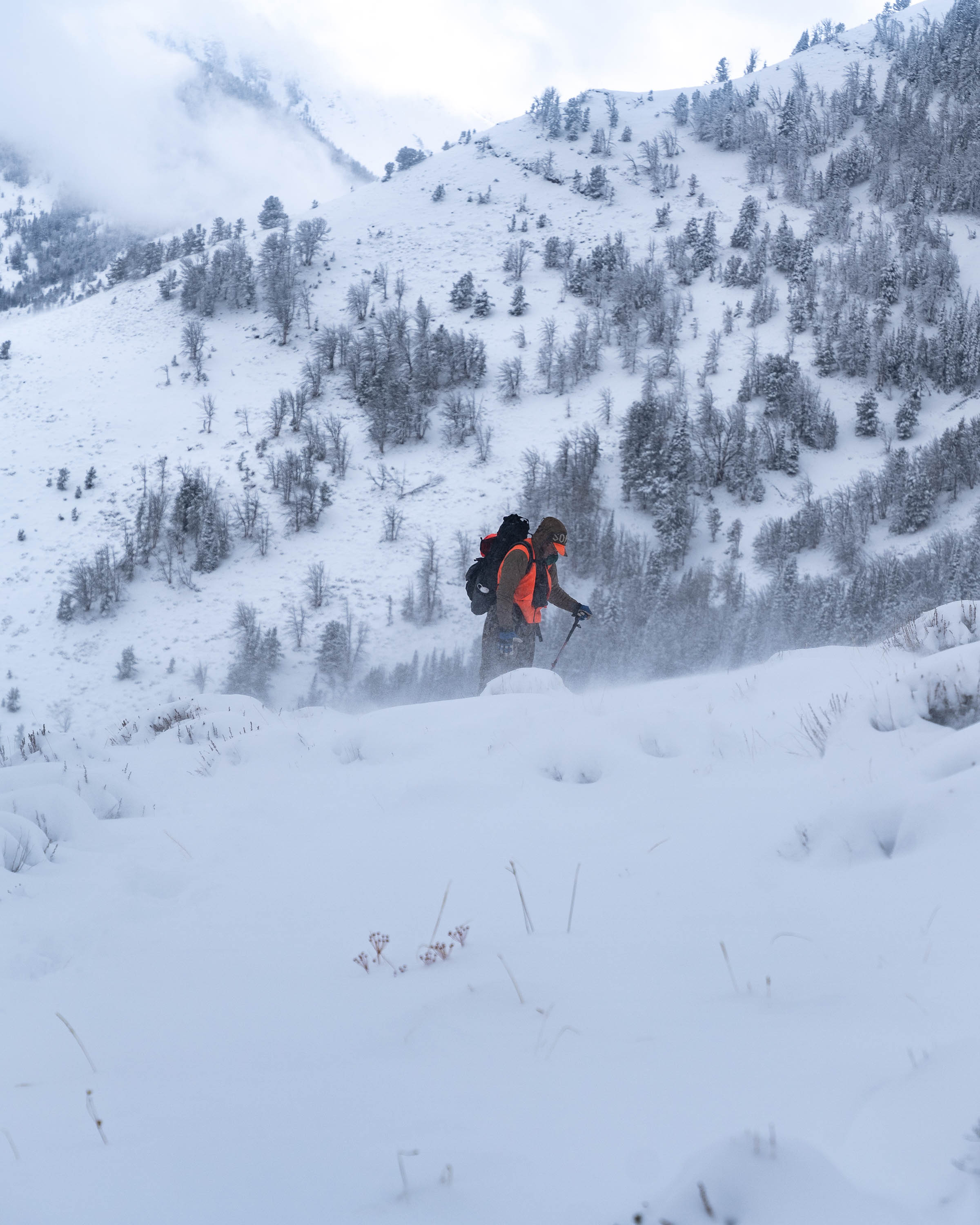 hunter trekking through heavy snow on steep snowey mountain